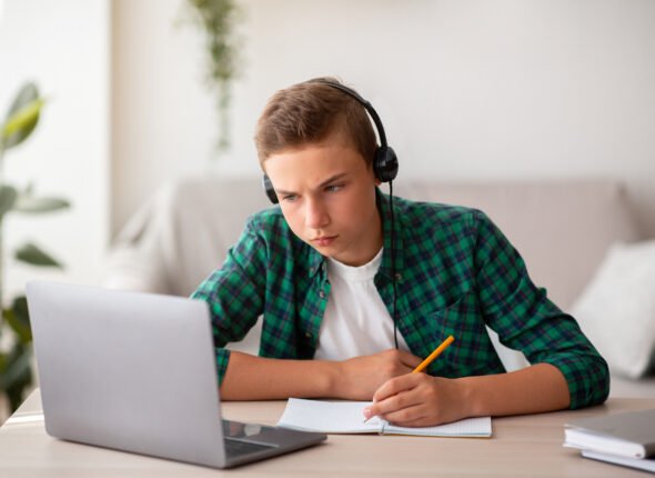 Concentrated school boy studying online from home