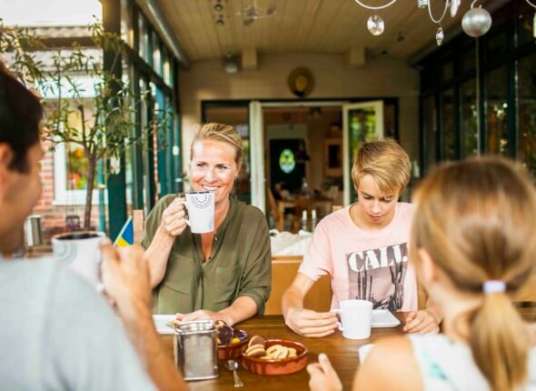 Happy parents with children enjoying art of small talk and having breakfast at home